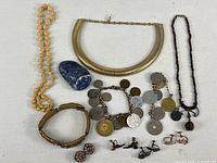Full lot of assorted costume jewelry laid out on white background featuring necklaces, bracelets, earrings, and polished stone.