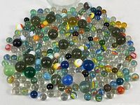 Close-up photo of assorted marbles showing various sizes and colors including clear and swirl patterns.