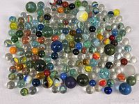 Lot of colorful vintage marbles of various sizes, displayed on a white surface.