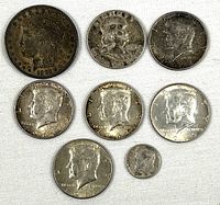 Top view of seven vintage U.S. silver coins including Morgan Dollar, Franklin Half Dollar, Kennedy Half Dollars, and Roosevelt Dime.