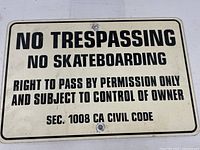 Front of metal sign showing black text on white background with regulatory warning.