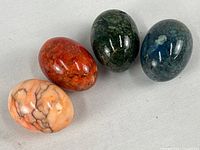 Four polished stone eggs showing color variations and glossy finish.