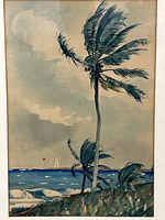 Closeup of framed print showing two coconut trees blowing in the wind against ocean and sky background.