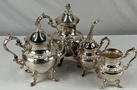 Full view of silver on copper coffee and tea service set showing all four pieces including coffee pot, tea pot, creamer, and sugar bowl.