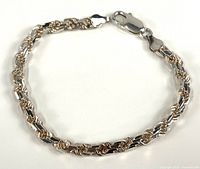 Full view of sterling silver rope chain bracelet with lobster clasp laid flat on white background.