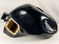 Side view showing black fuel tank with white Triumph logo and mounting area.