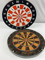 Both dartboards shown side-by-side on white background. Older round Sportcraft board has muted patina and the newer Pimm's board has bright red, white, and black sections with Pimm's lettering.