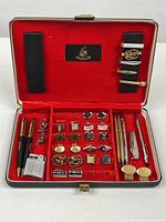 Open vintage Swank case displaying complete set of men's accessories including cufflinks, pens, tie clips, and lighter arranged in red velvet lining.
