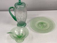 Overview of the three items including pitcher, plate, small compote, and ladle on table