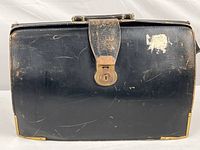 Front view of the vintage leather briefcase showing scratches, wear, and a brass locking clasp.