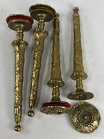 Four vintage solid brass table legs with detailed floral patterns and screw-on plates with felt pads underneath