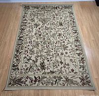 Full view of ivory leaf patterned rug on wooden floor