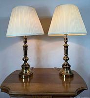 Both brass lamps with shades illuminated on table