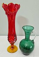 Full view of the amberina swung vase beside the green glass pitcher