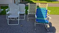Group shot showing three grey folding chairs and one knitted webbing rocking chair
