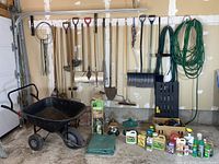 Overall lot with wheelbarrow, hanging tools, hoses, chemicals