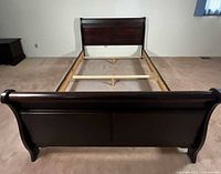 Full view of assembled sleigh bed frame showing headboard, footboard, rails and supports