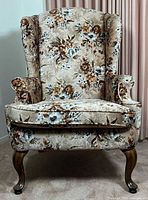 Front view of floral wingback chair showing overall design and legs