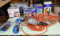 Group shot of five boxed spotlights, trouble lamp with orange cord, timer package and block-heater cord