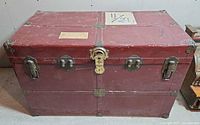 Front view of red vintage trunk with hardware visible