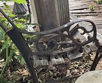 Left side bench frame with scrollwork and damaged wood slats