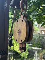 Full view of hanging wooden pulley showing wood cheeks, iron hook and bottom becket