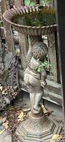 Full view of pedestal bird bath showing cherub figure, scalloped basin, corrosion and paint wear