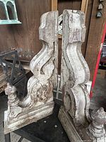 Front three-quarter view of both corbels showing scroll carving and distressed paint
