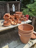 Overview of assorted terracotta pots and saucers on picnic table