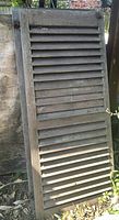 Front view of single weathered wood louvered shutter