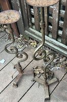 Full view of both wrought iron candle holders showing scroll stems and tripod bases