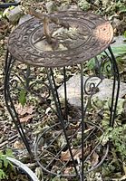 Full view of cast iron sundial on wrought iron stand in garden setting