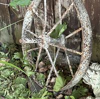 Front view of rusted metal wagon wheel among leaves