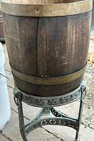 Wooden bucket with brass-tone bands on ornate cast iron stand