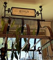 Full view of metal pot rack hanging from ceiling with hooks and wine label plaque