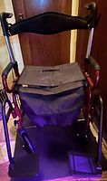 Front view of red folding transport wheelchair with footrests and pouch