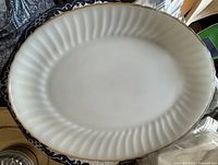 Top view of white glass oval platter showing fluted edge and gold rim
