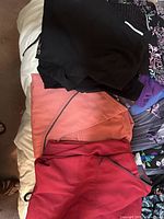 Stack of black, coral and red scrub garments