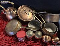 Overall view of copper cookware lot on red mat