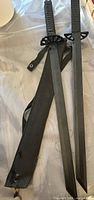 two black metal training swords and nylon sheath full view