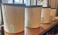 Four white canisters in descending order without lids