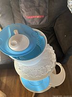 All components of Tupperware salad spinner stacked on small table: outer bowl, inner basket, lids, spinning mechanism visible
