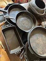 Overview of stacked cast iron pieces including loaf pan, skillet, kettle