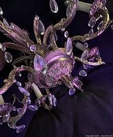 Bottom view showing ornate central boss, arms, glass prisms, candle sleeves