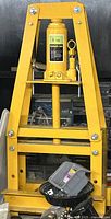 Front view of yellow 6-ton hydraulic shop press with bottle jack installed