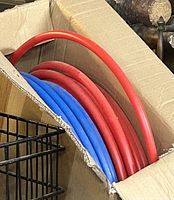 Red and blue PEX tubing coils inside cardboard box