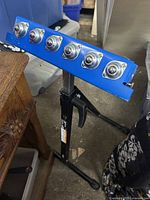 Full view of roller stand showing blue ball transfer bar and black adjustable stand