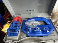 open case showing blue jig base, handle, four spacer rings