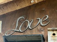 Overall view of metal “Love” sign mounted on wall showing size and design