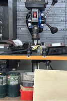 Front view of Mastercraft bench-top drill press with clamps attached to bench and parts below